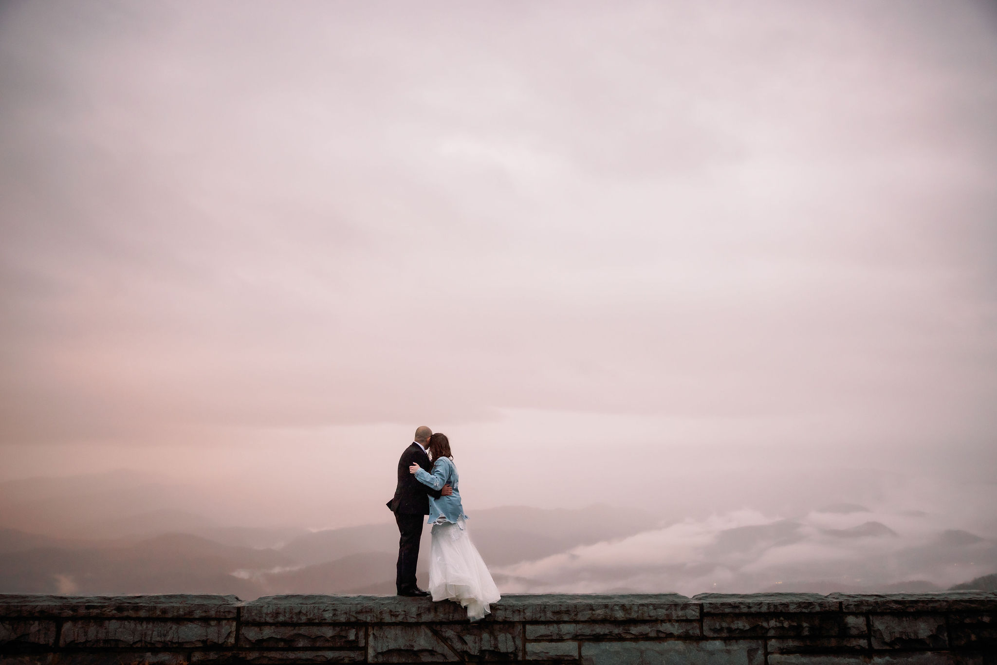 pink sunset in the clouds over the mountains with bride and groom kissing sweetly in the forefront for Gatlinburg elopement