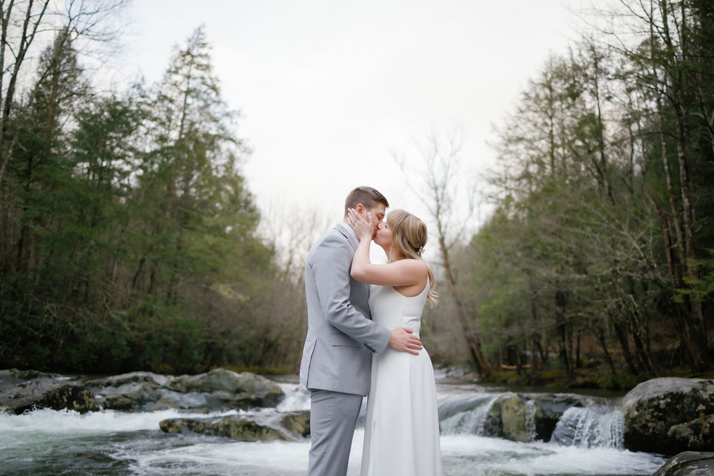 Greenbrier elopement with bride and groom kissing as they stand in the river together