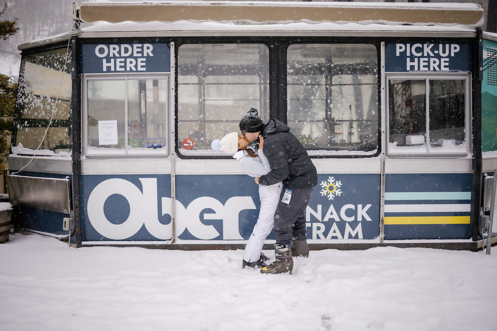 ober mountain proposal with couple kissing in the snow in front of the ticket office for a unique place to propose in Gatlinburg